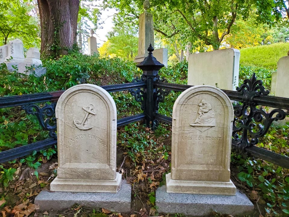 Pair of tombstones in the corner of a fenced plot.