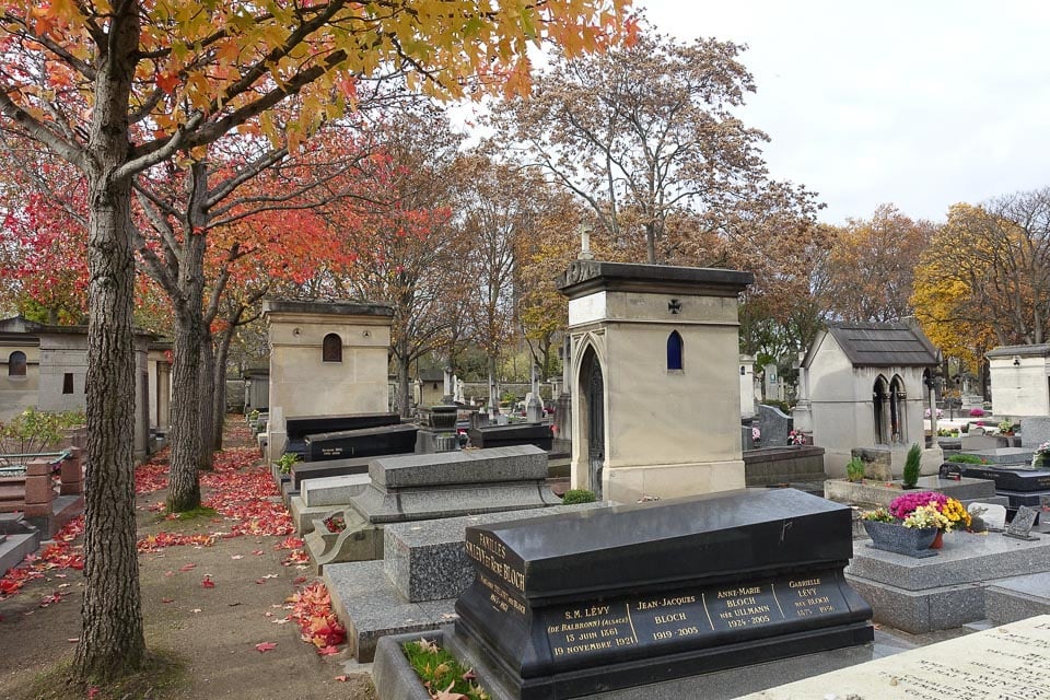 Graves in Montparnasse Cemetery with colourful autumn trees.