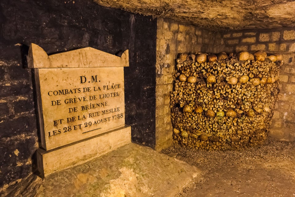 Inscribed tablet with bones stacked in the corner of a tunnel.