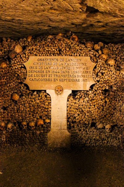 Sign in front of a wall of bones in the Paris underground ossuary.