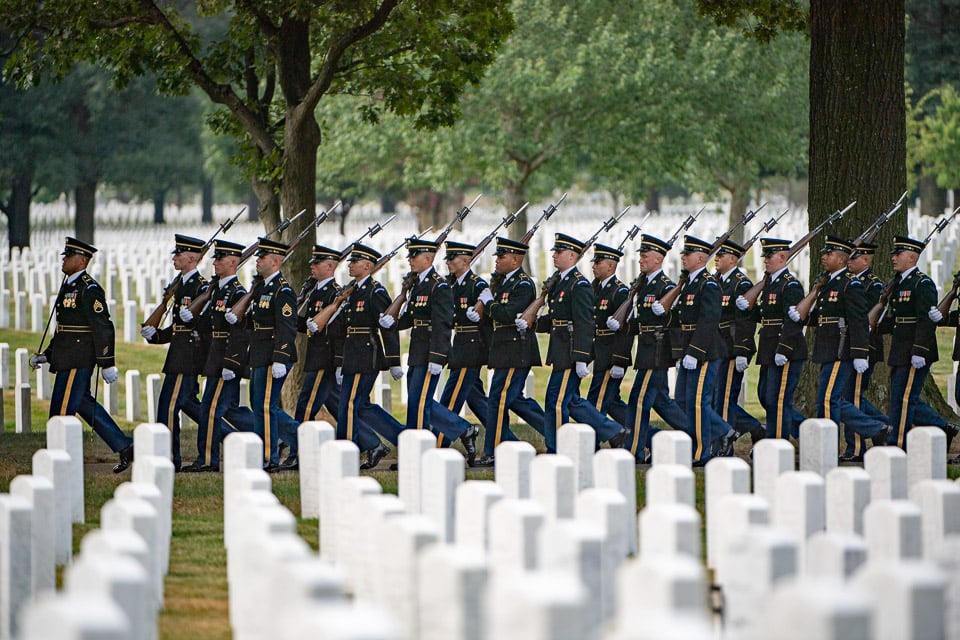Soldiers marching among the graves in Arlington National Cemetery.