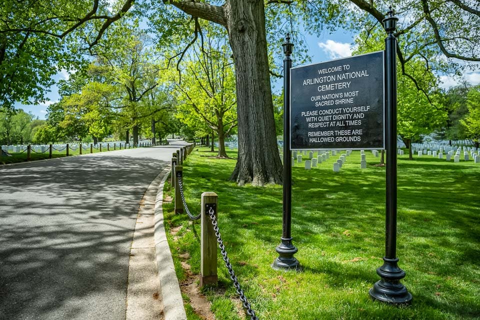 Welcome to Arlington National Cemetery sign beside a road in the cemetery.