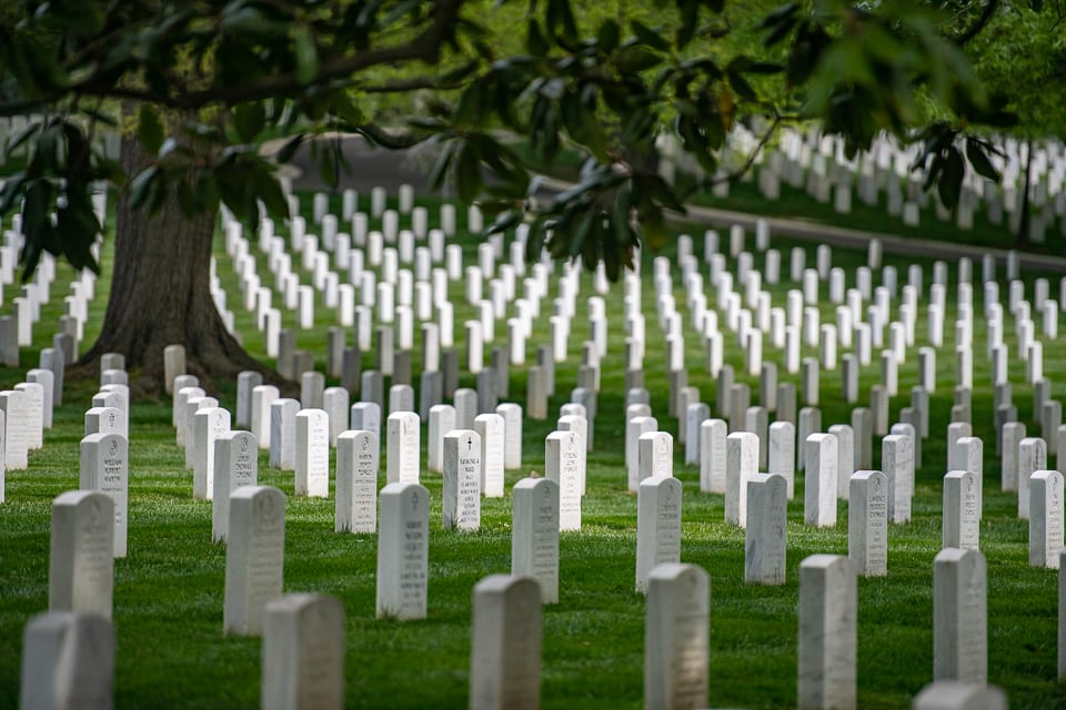Rows of tree-shaded graves in Arlington National Cemetery.