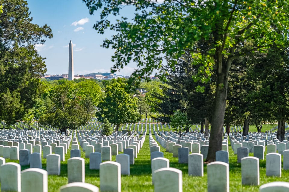 Rows of graves in Arlington National Cemetery with the Washington Monument in the background.
