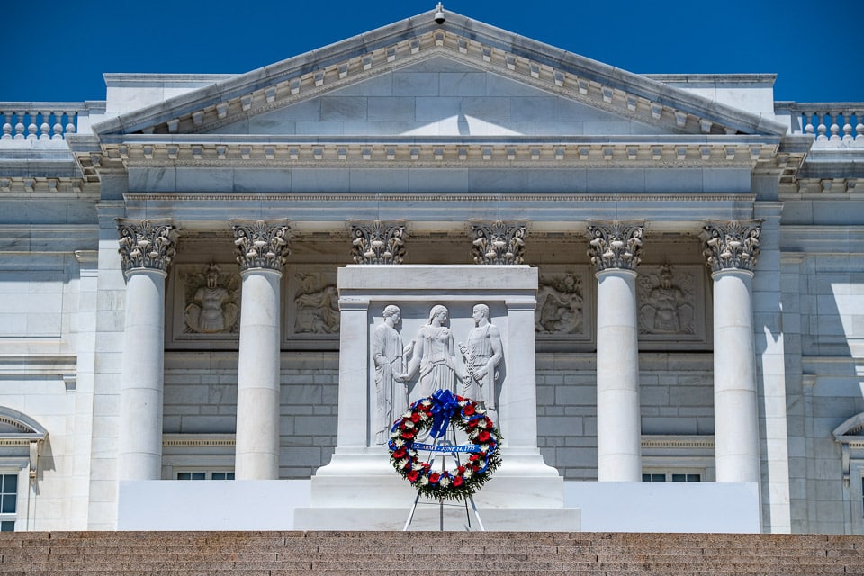 Red and white wreath in front of the tomb with Memorial Amphitheater in the background.