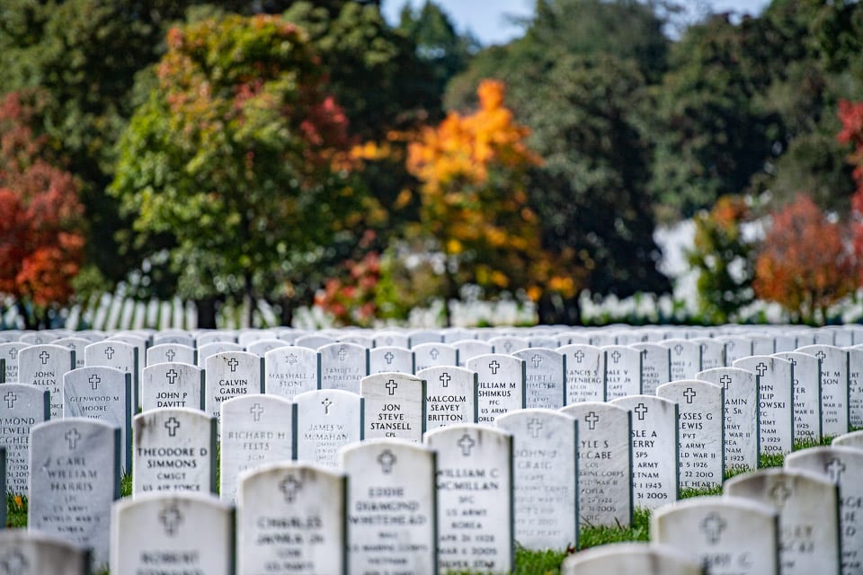 Rows of tombstones with autumn trees in the background.