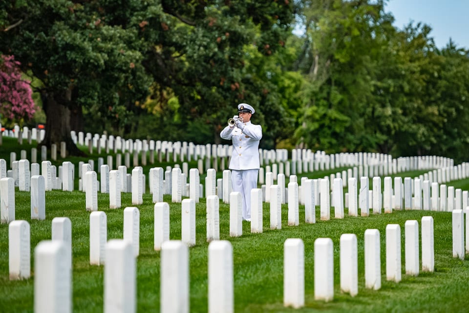 Soldier playing a trumpet among the tombstones in Arlington National Cemetery.