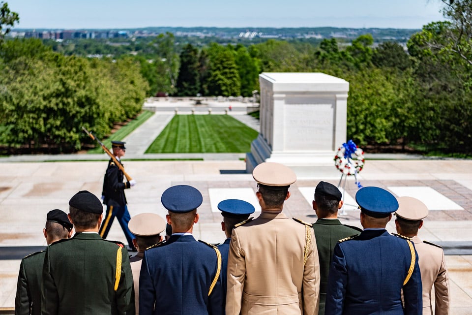Military members watching a soldier walk the mat at Arlington National Cemetery's Tomb of the Unknown Soldier.