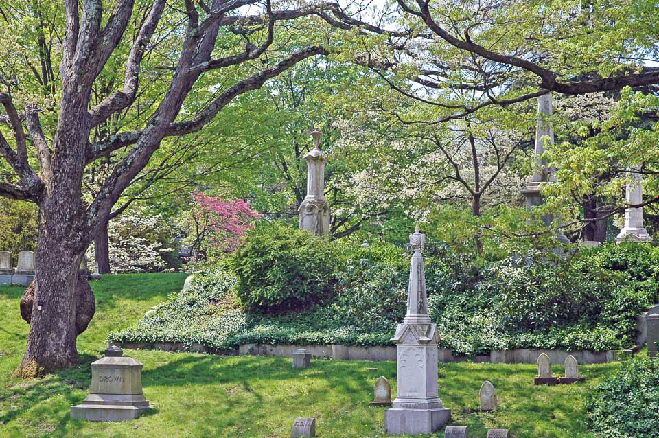 Trees and gardens surround grave markers and funerary art in Mount Auburn Cemetery.