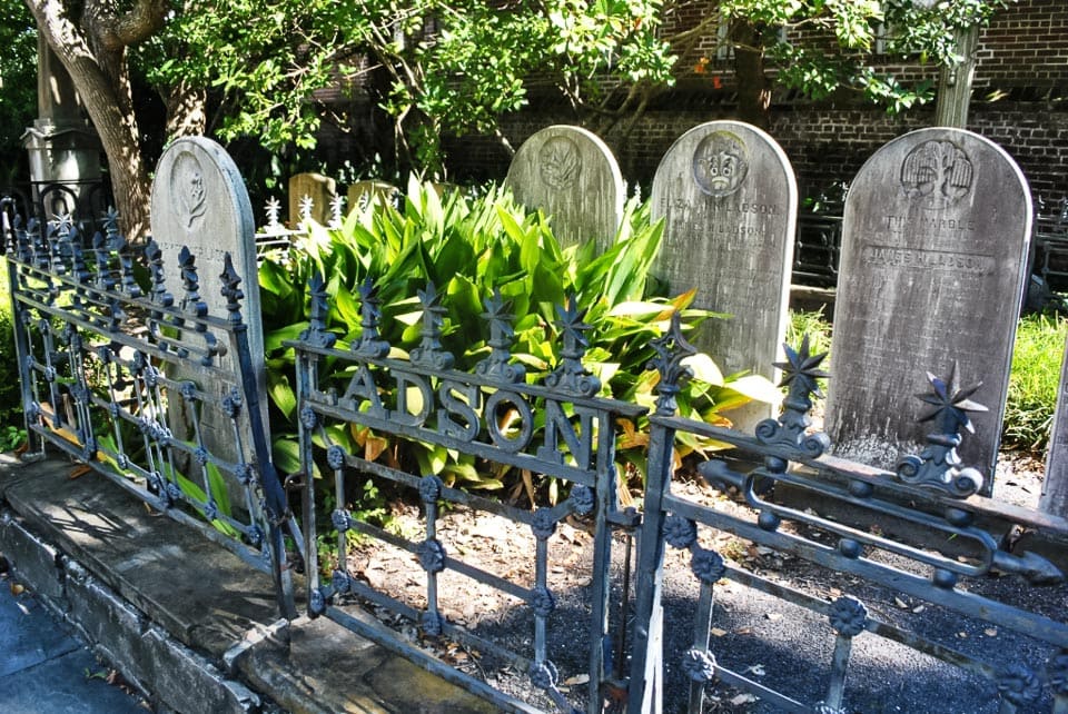 Tombstones behind an iron fence.