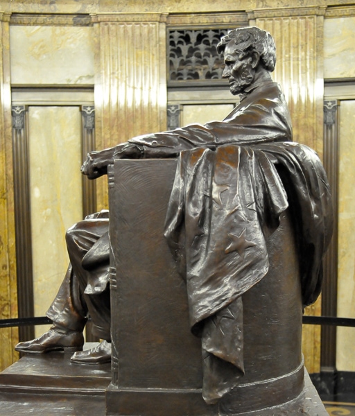 Side view of a sculpture of Lincoln sitting in a chair.