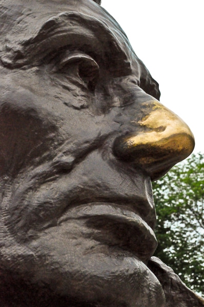 Close up of the shiny gold nose on Lincoln's bust outside his tomb.