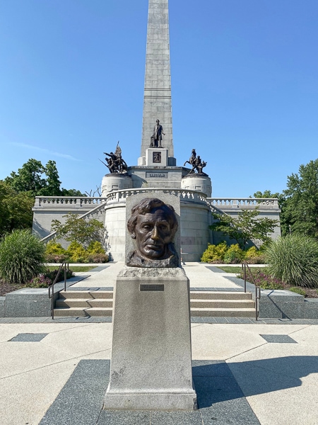 Bust of Abraham Lincoln in front of the Lincoln Tomb building.