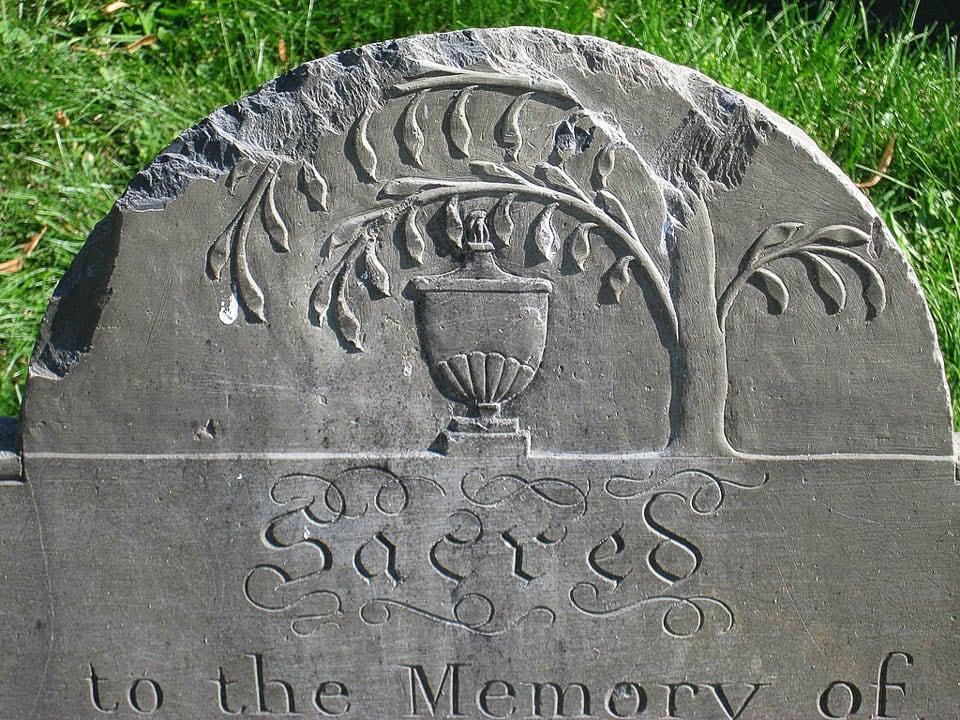 A tree and urn carved onto a tombstone.