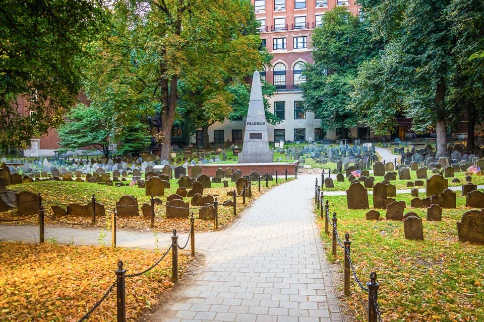 Sidewalk, obelisk, and graves in Granary Burying Ground, Boston.