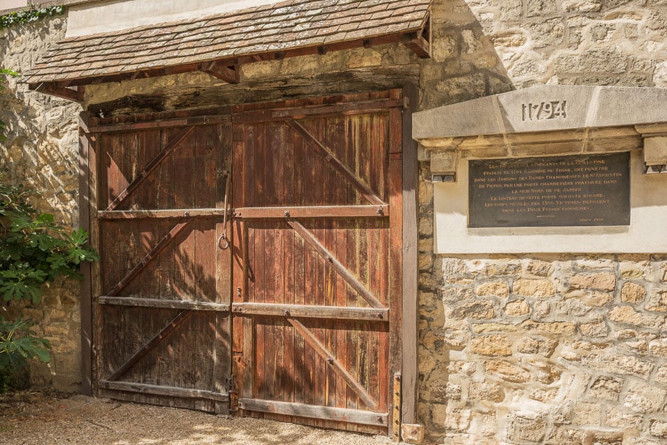 Wooden gate and stone wall at Picpus Cemetery.