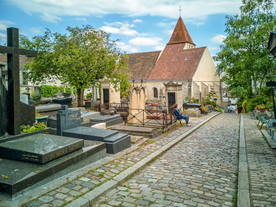 Graves, cobblestone path and church in Charonne Cemetery.