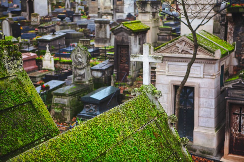 Mossy mausoleum roof with rows of tombs in the background.