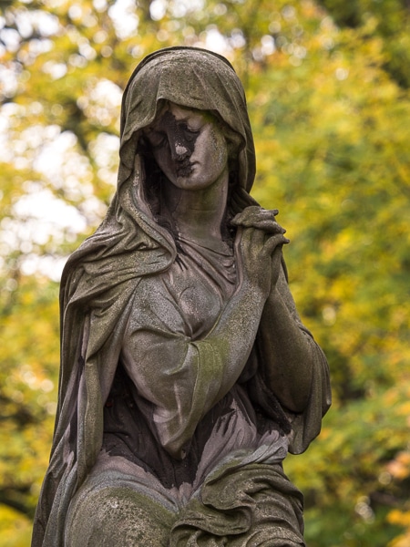 Stone sculpture of a mourning woman in draped clothing.