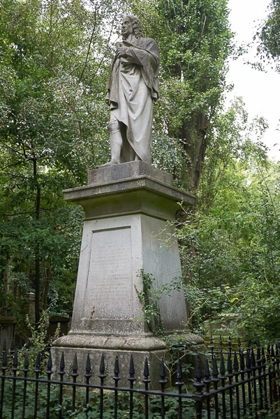 Monument with a sculpture of a man in in Abney Park Cemetery.