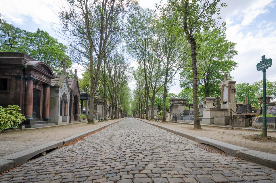Cobblestone path framed by tombs, mausoleums and trees.