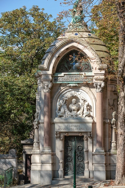 Ornate family mausoleum framed by trees.