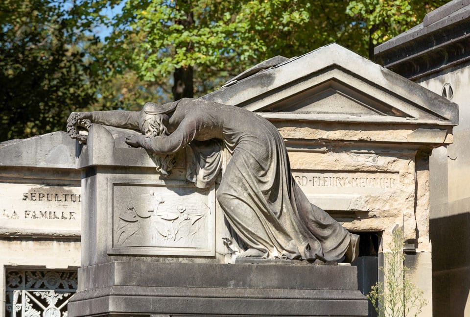 Sculpture of a mourning woman crying facedown on a tomb.