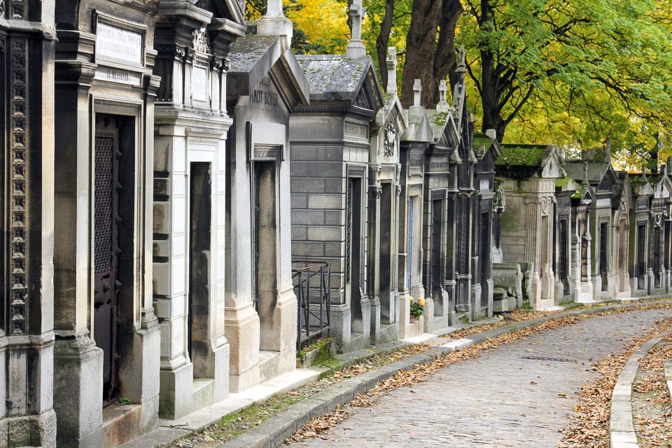 Cobblestone path lined with tombs in Pere Lachaise Cemetery.