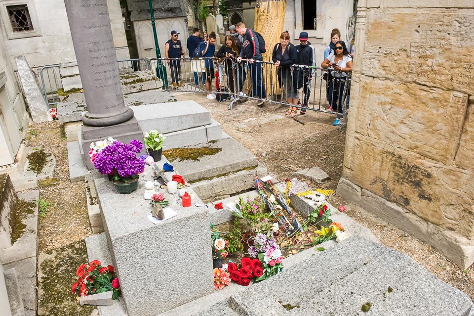 Fans gathering at the grave of Jim Morrison, one of the most famous graves in Pere Lachaise Cemetery.