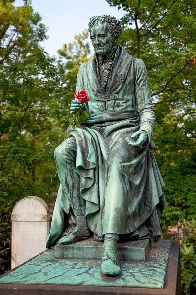 Bronze sculpture of a man holding a rose on the grave of Vivant Denon.
