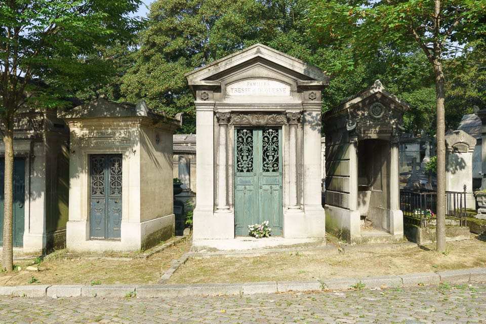 Tombs beside a cobblestone path in Pere Lachaise Cemetery.