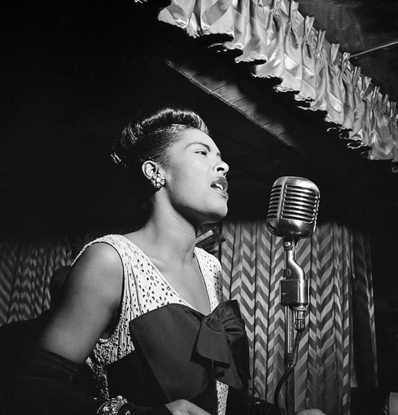 Black and white photo of Billie Holiday performing.